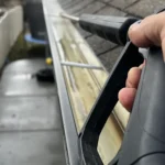 Residential gutter being cleaned with a pressure washer