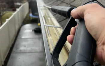 Residential gutter being cleaned with a pressure washer