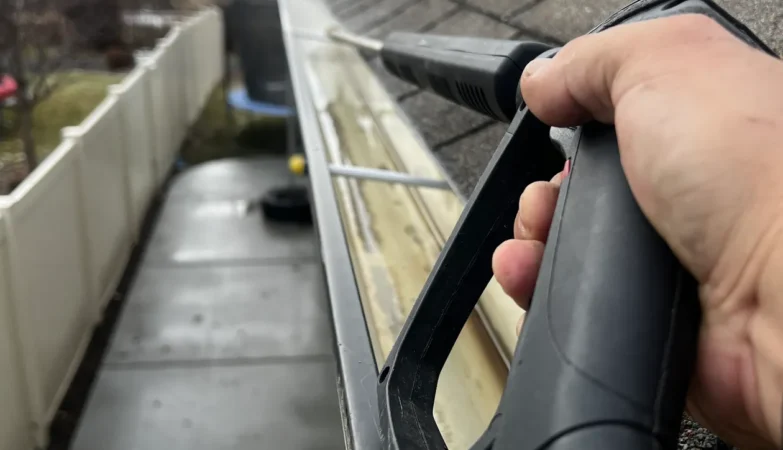 Residential gutter being cleaned with a pressure washer