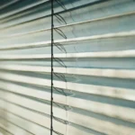 Close-up of white venetian blinds with sunlight
