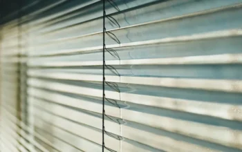 Close-up of white venetian blinds with sunlight