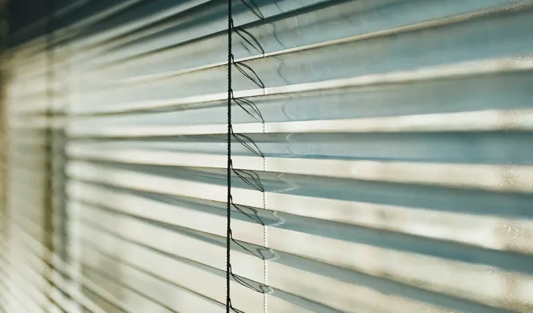 Close-up of white venetian blinds with sunlight