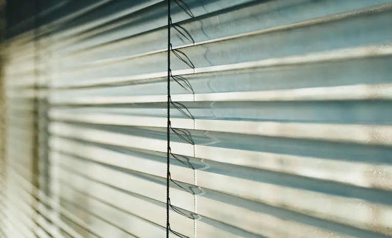 Close-up of white venetian blinds with sunlight