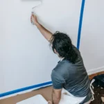 Person using a roller to paint a wall during a home renovation