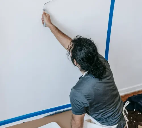 Person using a roller to paint a wall during a home renovation