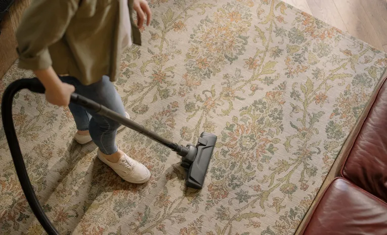 Woman vacuuming a patterned carpet at home